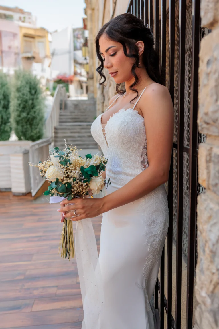 Novia con ramo apoyada en una fachada de piedra durante su boda en Jaén