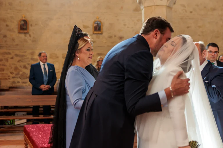 Novios besándose durante la ceremonia religiosa en una iglesia de Jaén ante familiares.