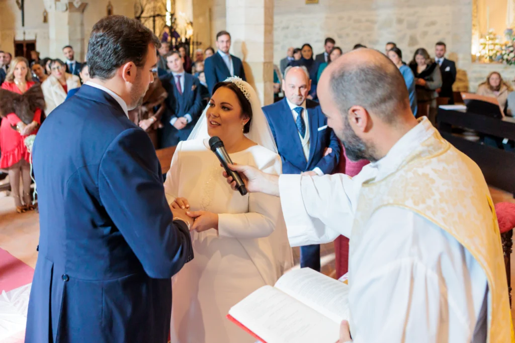 Intercambio de anillos durante una ceremonia religiosa en una iglesia de Jaén con el sacerdote oficiando.