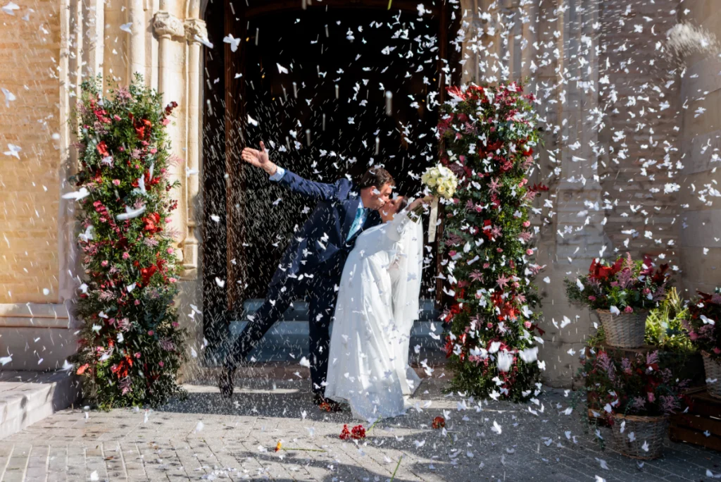 Novios celebrando bajo una intensa lluvia de pétalos a la salida de la iglesia en Jaén
