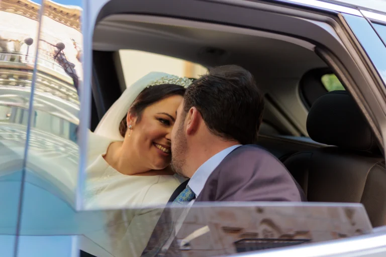 Novios sonriendo dentro del coche recien casados compartiendo un momento íntimo y romántico.