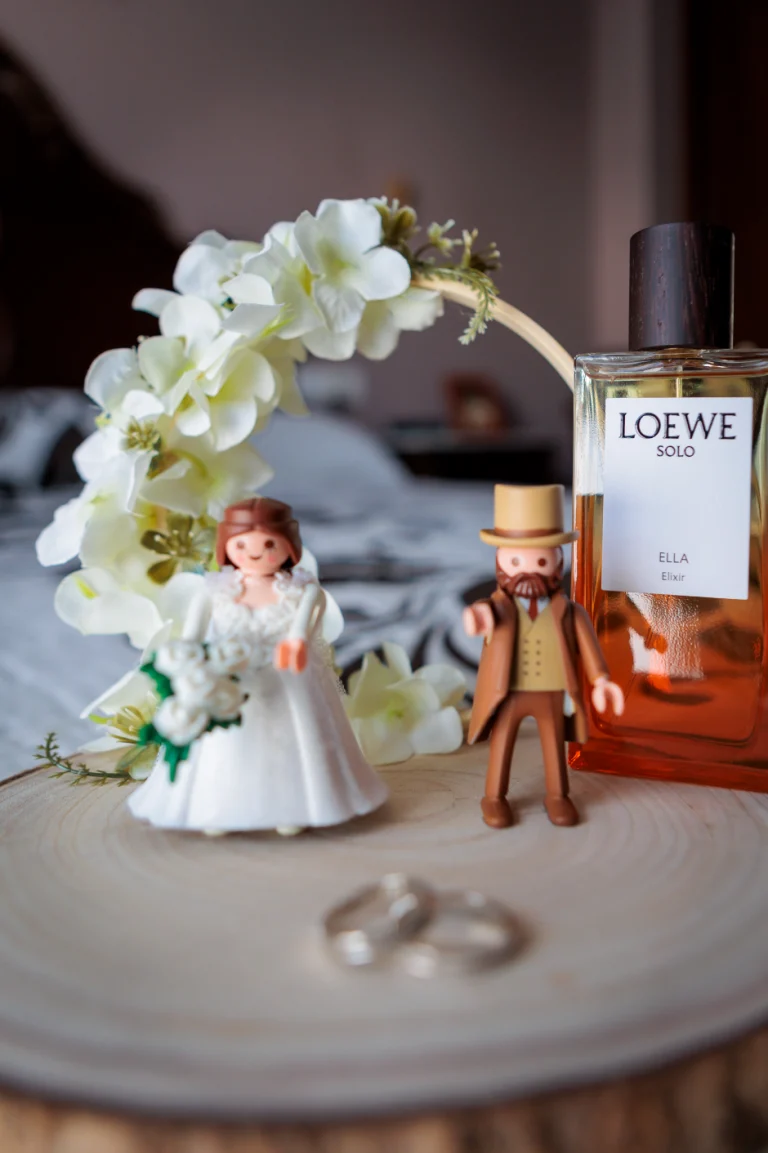 Detalle de alianzas de boda junto a perfume y figuras decorativas durante los preparativos en Jaén.