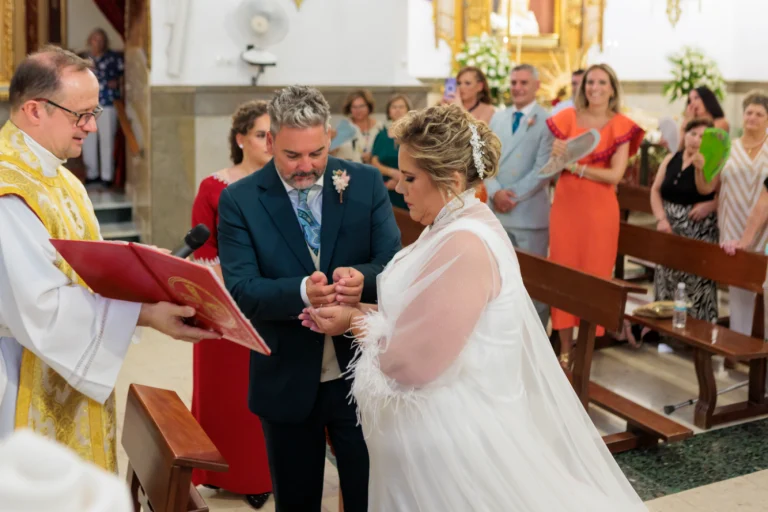Intercambio de las arras durante la ceremonia religiosa en una iglesia de Jaén con los novios y el sacerdote
