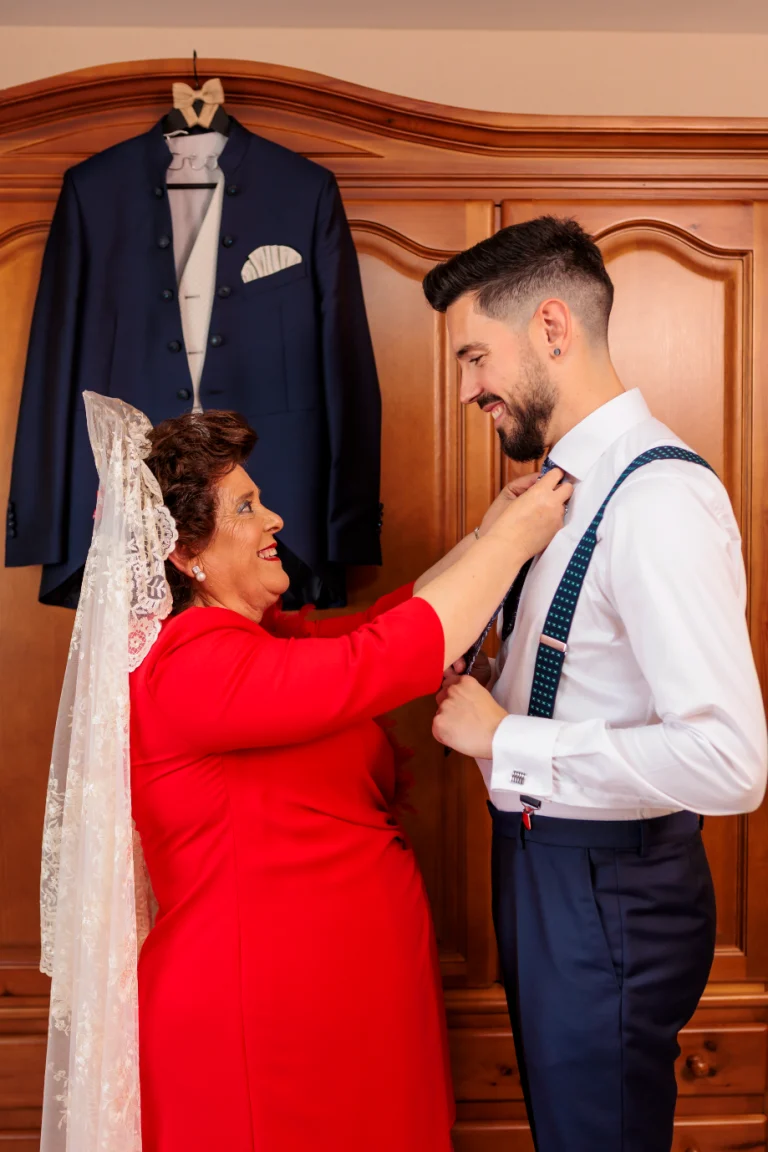 Madrina ayudando al novio con la corbata antes de la ceremonia