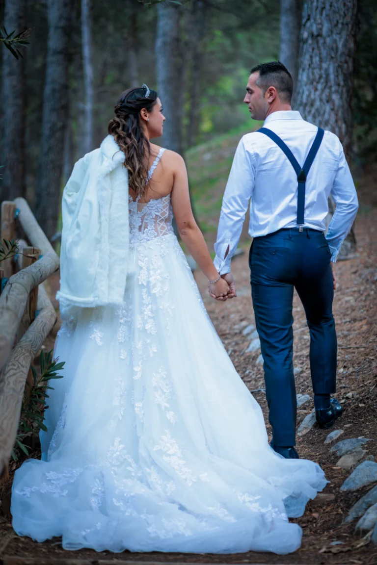 Novios caminando de la mano por un sendero de bosque durante su reportaje de boda en exterior