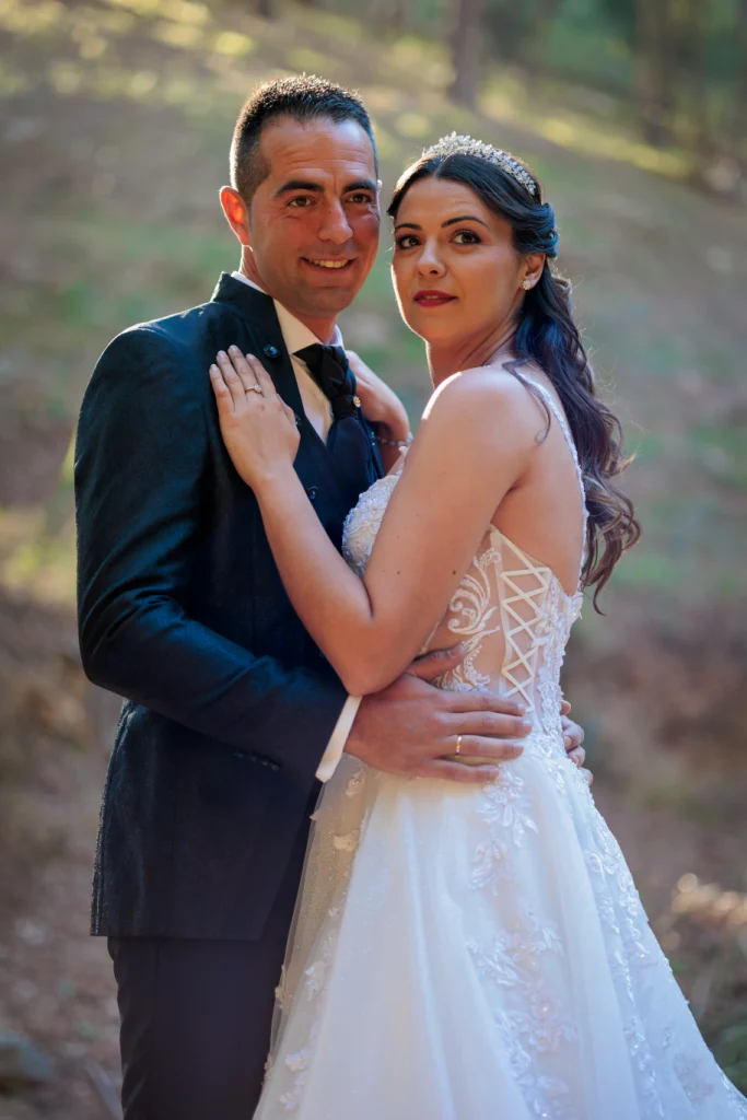 Novios abrazados mirándose a cámara durante su sesión postboda en la naturaleza en Jaén.