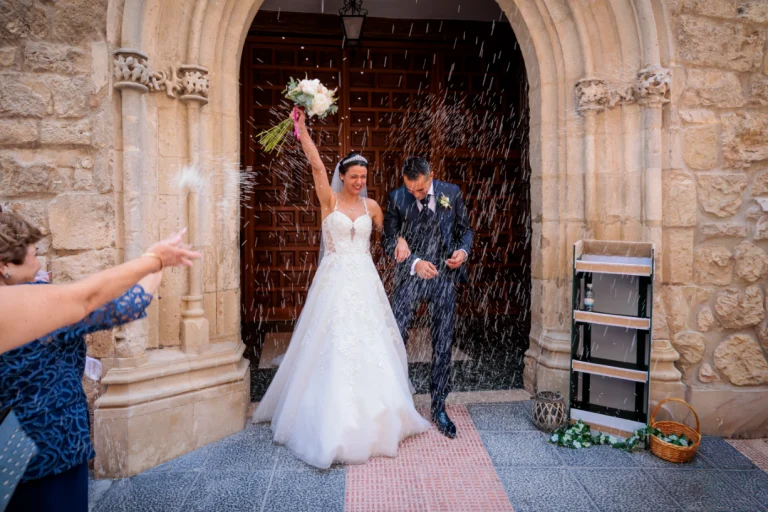 Novios saliendo de la iglesia bajo una lluvia de arroz tras su boda en Jaén.