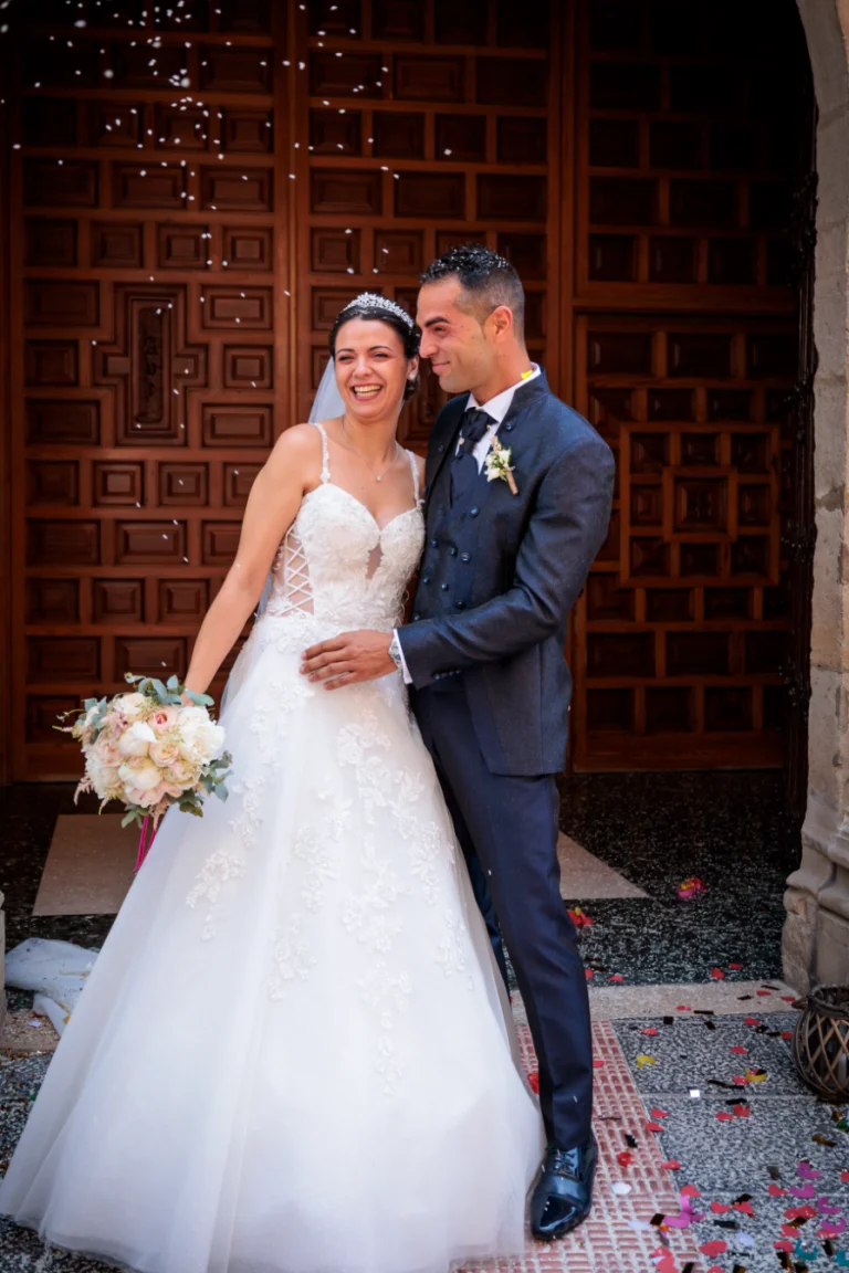 Novios recién casados sonriendo a la salida de la iglesia tras la ceremonia de boda en Jaén.