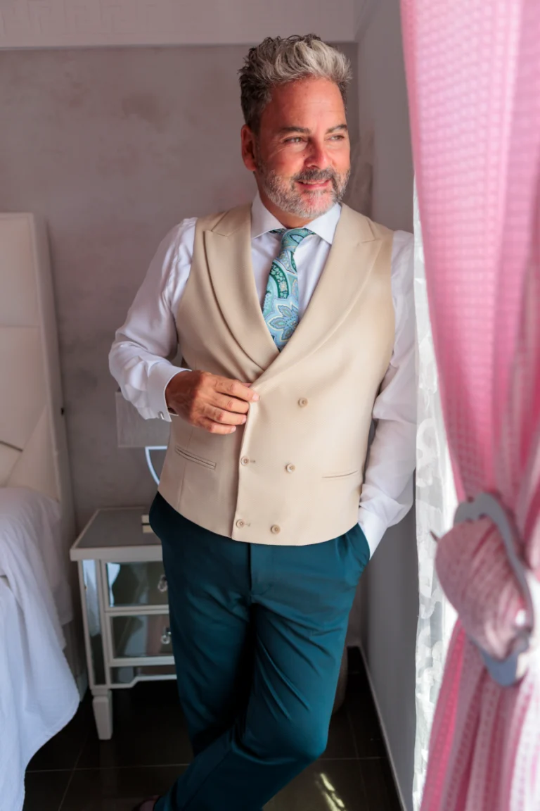 Novio elegante mirando por la ventana durante los preparativos de su boda en Jaén.