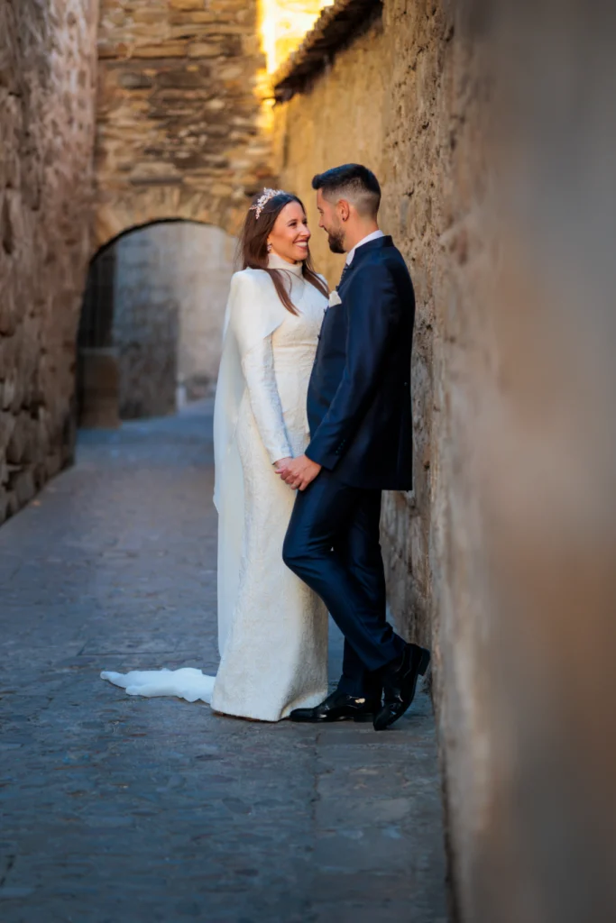Novios apoyados en un muro de piedra en Baeza durante su reportaje de boda en Jaén