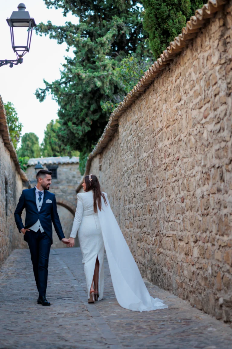 Novios caminando de la mano por una calle histórica de Baeza durante su boda en Jaén