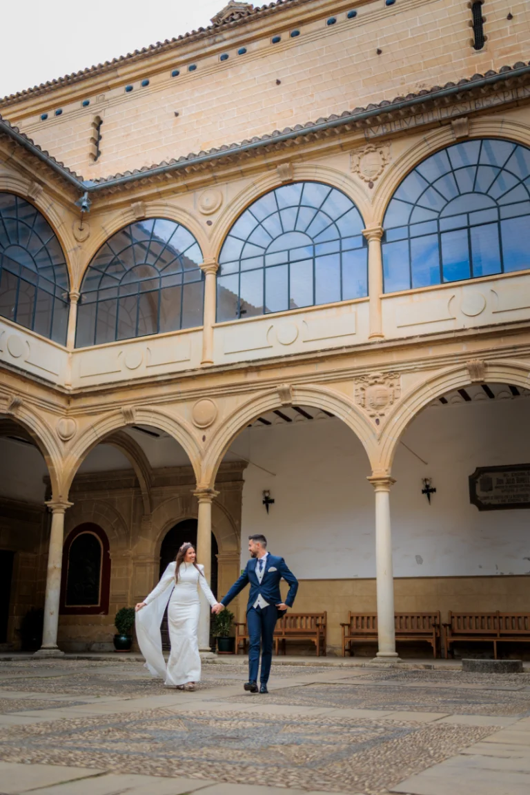 Novios caminando de la mano en el claustro histórico de Baeza durante su boda en Jaén